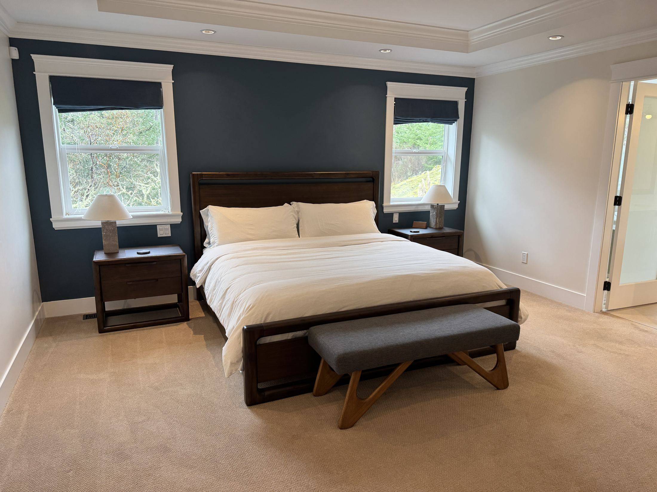 The primary suite: king bed, navy accent wall and a bench at the foot